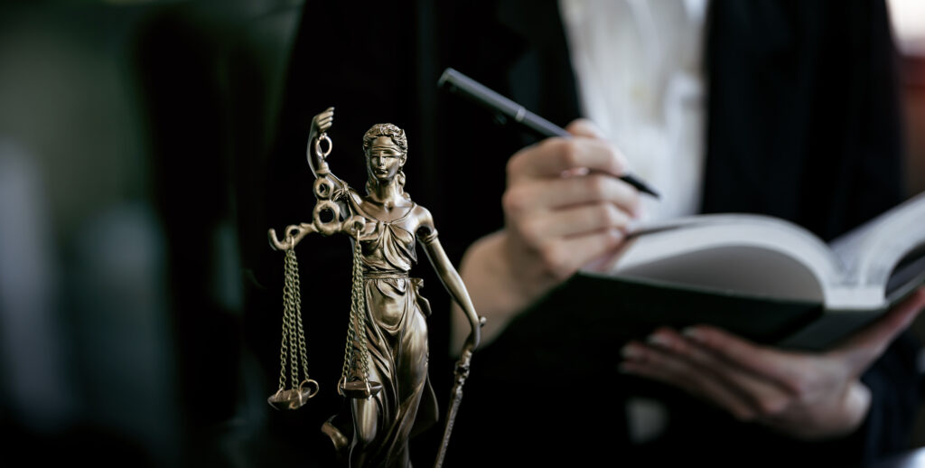 Statue Of Lady Justice, lawyer holding book in background.