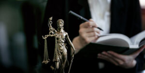 Statue Of Lady Justice, lawyer holding book in background.